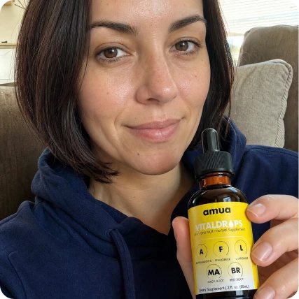 Customer with natural curls smiling and holding a VitalDrops bottle