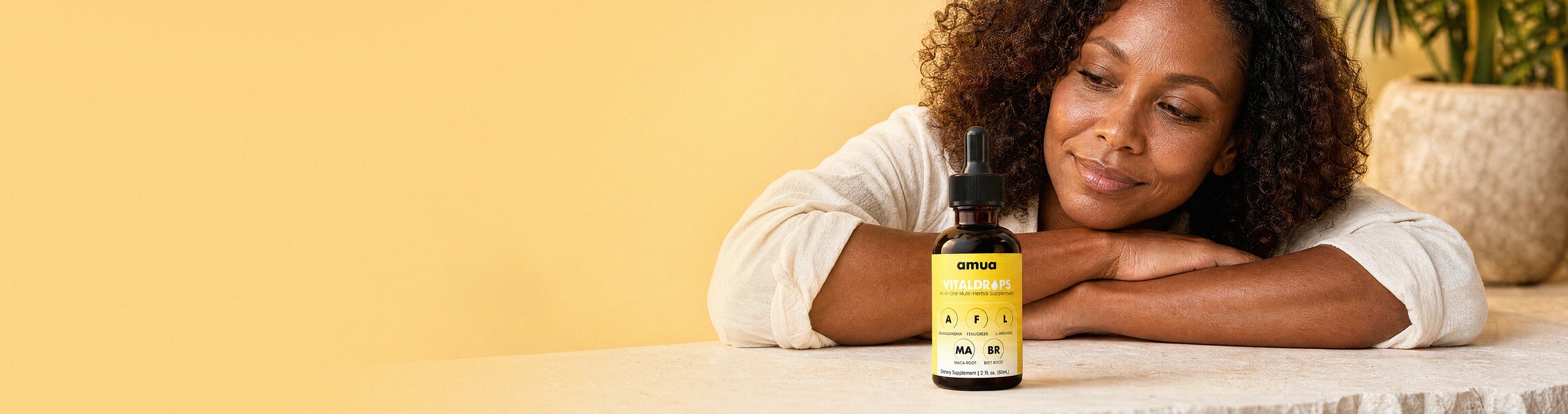 Smiling woman resting on her arms next to a bottle of Amua VitalDrops