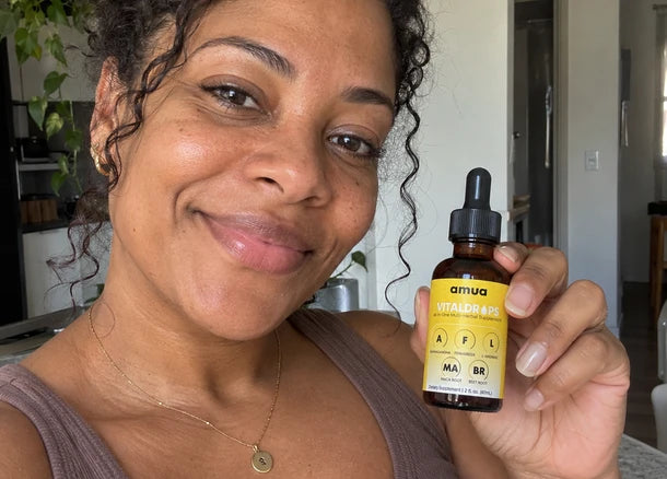 Customer with curly hair smiling and holding a VitalDrops bottle