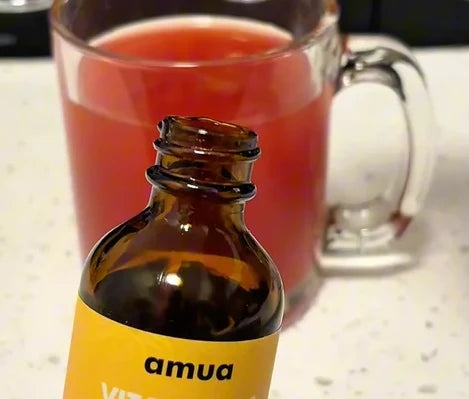 VitalDrops bottle in front of a glass of tea