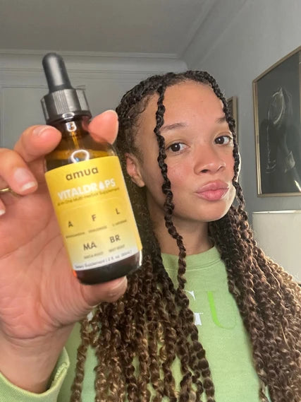 Customer with braids holding a VitalDrops bottle up to the camera